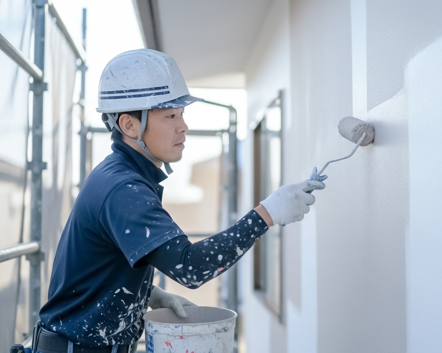 ローラーで外壁を塗装する職人のイメージ